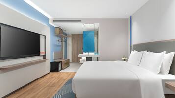A modern hotel room with a large bed, a flat-screen TV, a mirror, and a wardrobe.