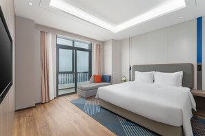 A modern hotel room with a large bed, a seating area with a view, and a balcony. - Holiday Inn Express Xiamen Jimei New Town by IHG (Xiamen)
