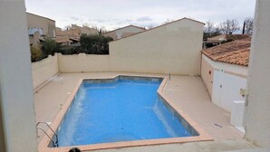 A rectangular swimming pool with a tiled edge, surrounded by a beige wall and a tiled roof. - Nice 3 room villa pool Rochelongue Cap d'Agde (LE CAP D AGDE)