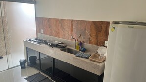 A modern kitchen with a marble backsplash, a gas stove, a sink, and a refrigerator. - Apto DE Luxo Standard 2 Quartos EM Caldas Novas (Olegário Pinto Caldas Novas)