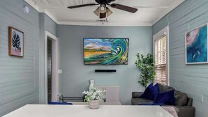 Una habitación moderna con una mesa blanca grande, un ventilador de techo y obras de arte en las paredes.