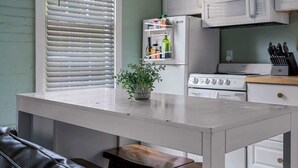 Una cocina con encimera blanca, un refrigerador, un microondas y una estufa.