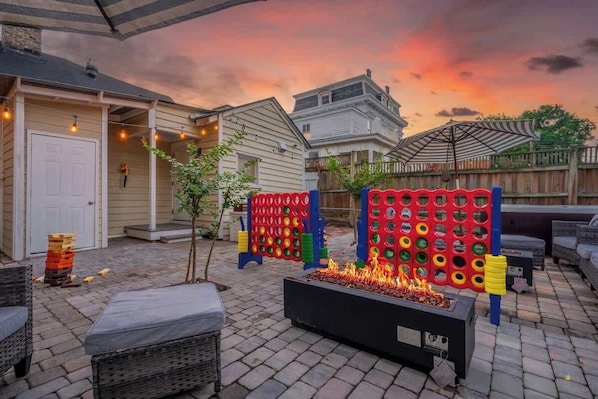 A backyard with a fire pit, outdoor seating, and a wooden fence.