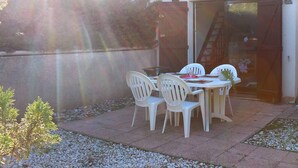 Eine Außenpatio mit Tisch und Stühlen, einer Pergola und Blick auf ein Gebäude mit einem Ziegeldach.