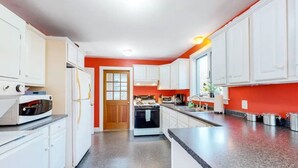 A modern kitchen with white cabinets, a granite countertop, and a red accent wall. -  "THE WAY LIFE SHOULD BE"
WATERFRONT OASIS /  HARBOR VIEWS AND A SHARED DOCK.
 (Cushing)
