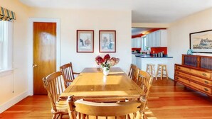 A dining room with a wooden table and chairs, a vase of flowers, and framed pictures on the wall. -  "THE WAY LIFE SHOULD BE"
WATERFRONT OASIS /  HARBOR VIEWS AND A SHARED DOCK.
 (Cushing)