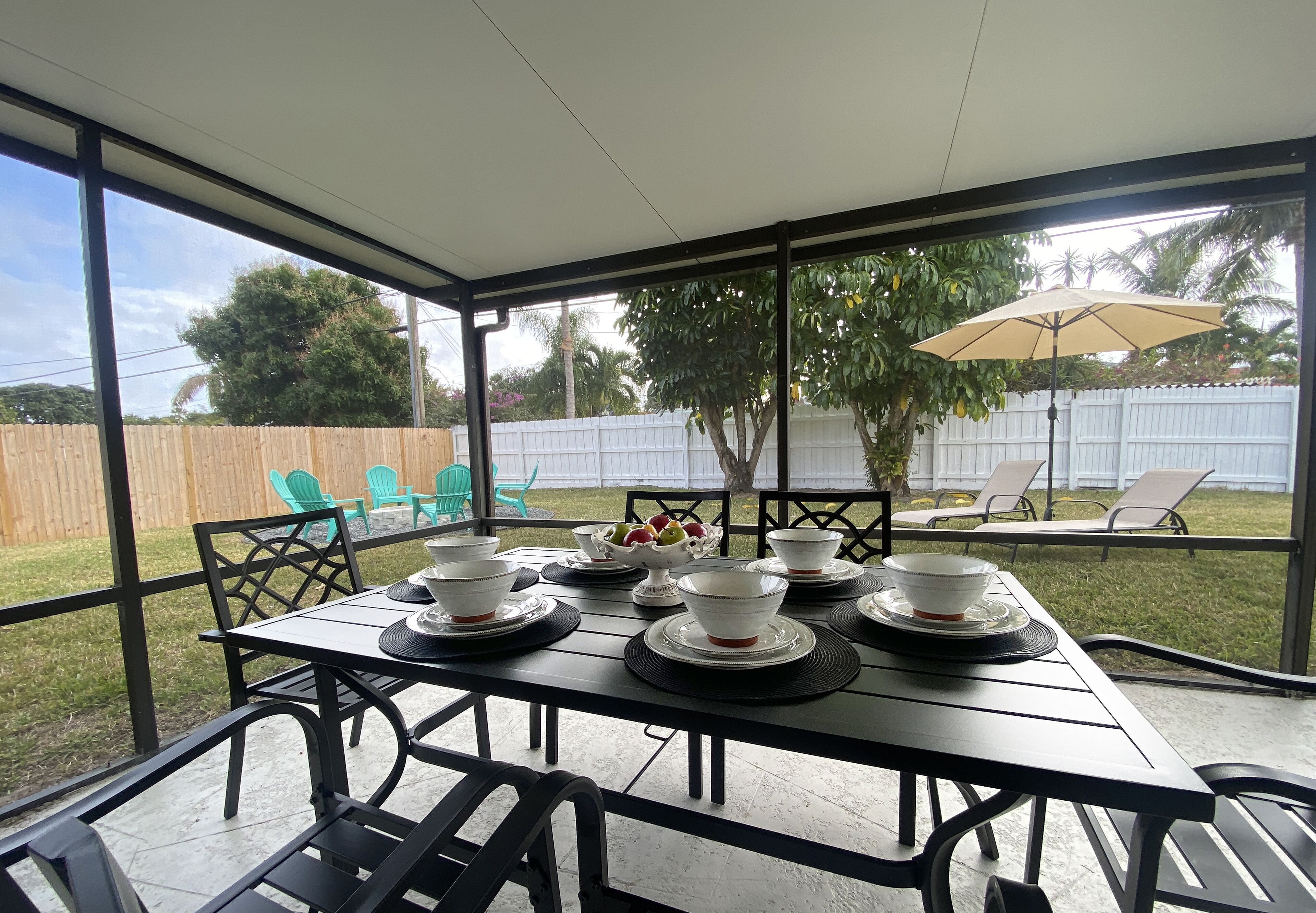 Un porxo cobert amb una taula ben a punt per a quatre, cadires d'exterior i vista al jardí.