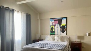 Ein Schlafzimmer mit Bett, Nachttisch, Lampe und einem Bild an der Wand.