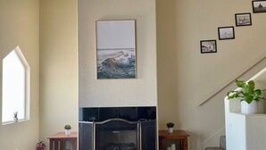 Ein Wohnzimmer mit Kamin, Fenster und Treppe.