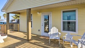 A yellow house with a wooden deck, white chairs, and a glass door. - Sun-Filled 3 Bedroom House - Steps from the Beach (Surfside Beach)