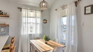 A dining area with a wooden table, white chairs, and a hanging light fixture. - Sun-Filled 3 Bedroom House - Steps from the Beach (Surfside Beach)