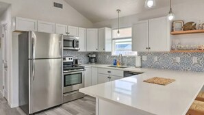 A modern kitchen with stainless steel appliances, white cabinetry, and a large island. - Sun-Filled 3 Bedroom House - Steps from the Beach (Surfside Beach)
