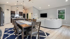 A modern kitchen with a dining area, a large window, and a ceiling fan. - Tranquil Jewel: Arcade, King Suits, Hot Tub, Decks (Sand Lake)