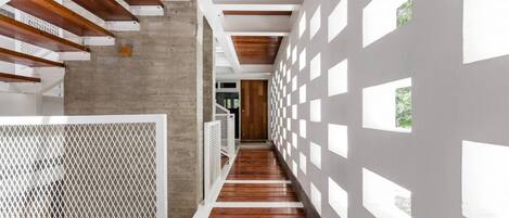 A modern interior with a wooden floor, concrete walls, and a series of white panels with cut-out windows.