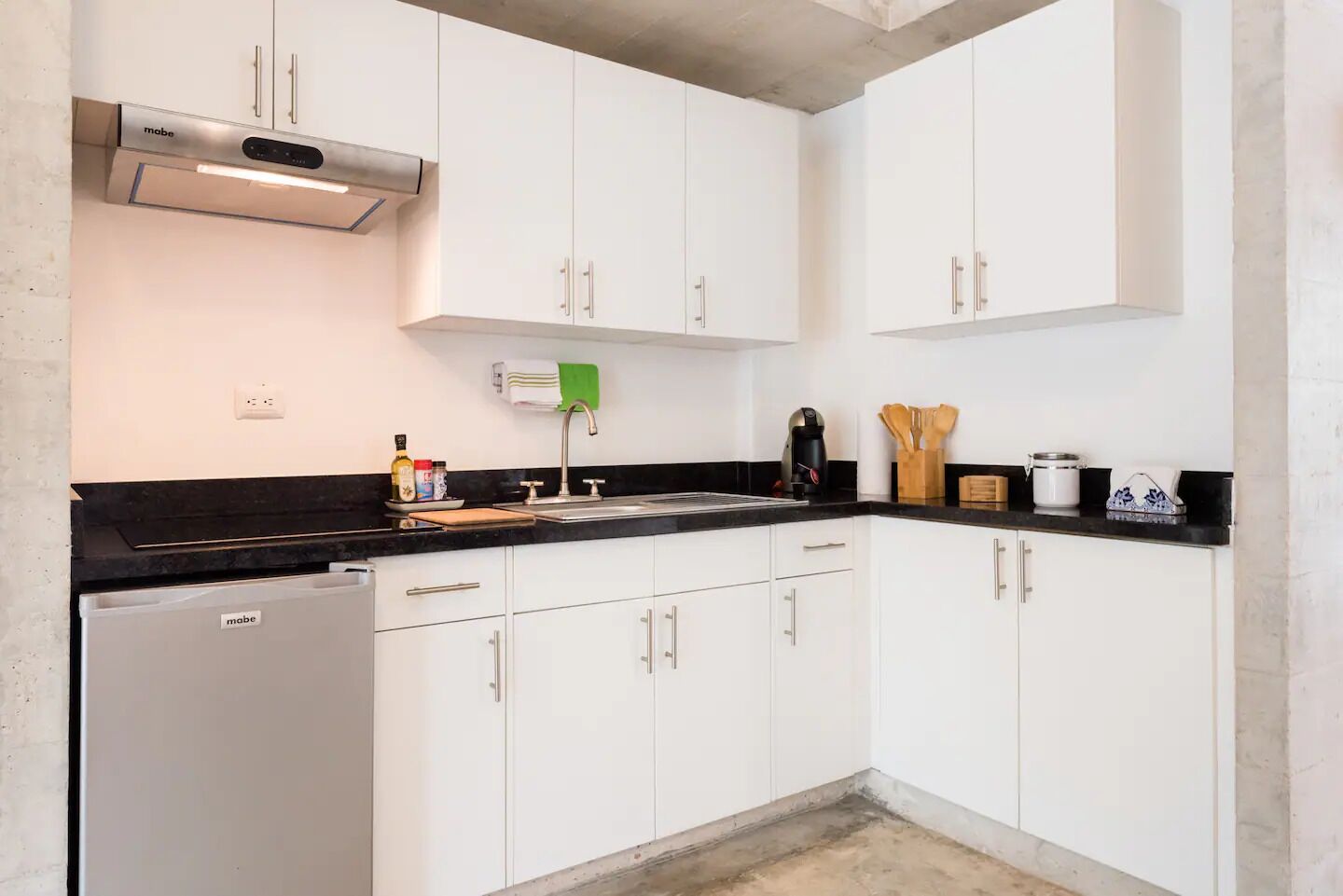 A modern kitchen with white cabinets, a black countertop, and a built-in dishwasher.