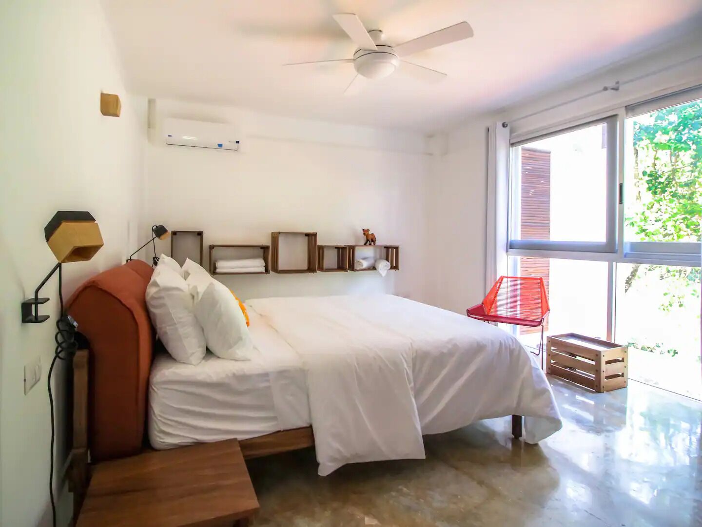A bedroom with a bed, a ceiling fan, a window, and a red chair.