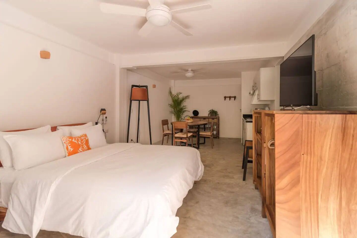 A hotel room with a bed, a desk, a chair, a television, and a ceiling fan.