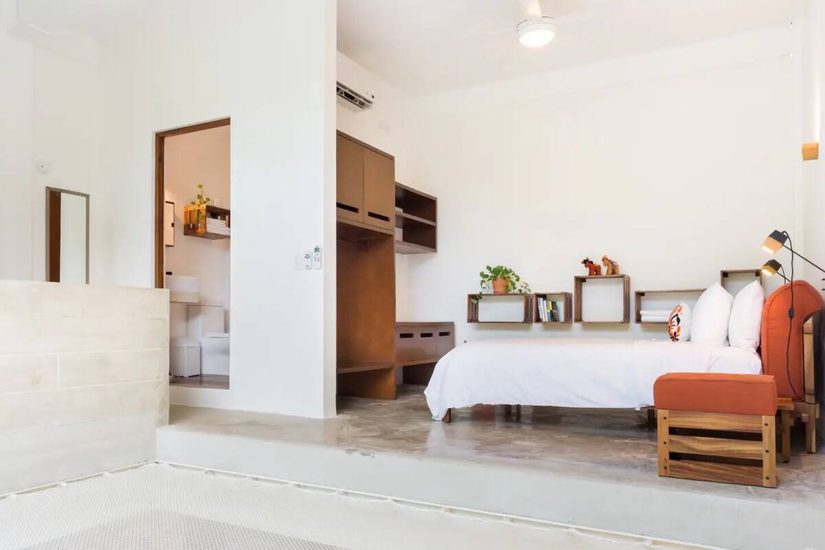 Una habitación de hotel moderna con cama, zona de estar y una kitchenette pequeña.