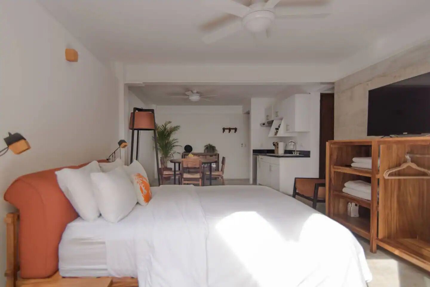 A bedroom with a bed, a wooden wardrobe, a desk, and a chair.