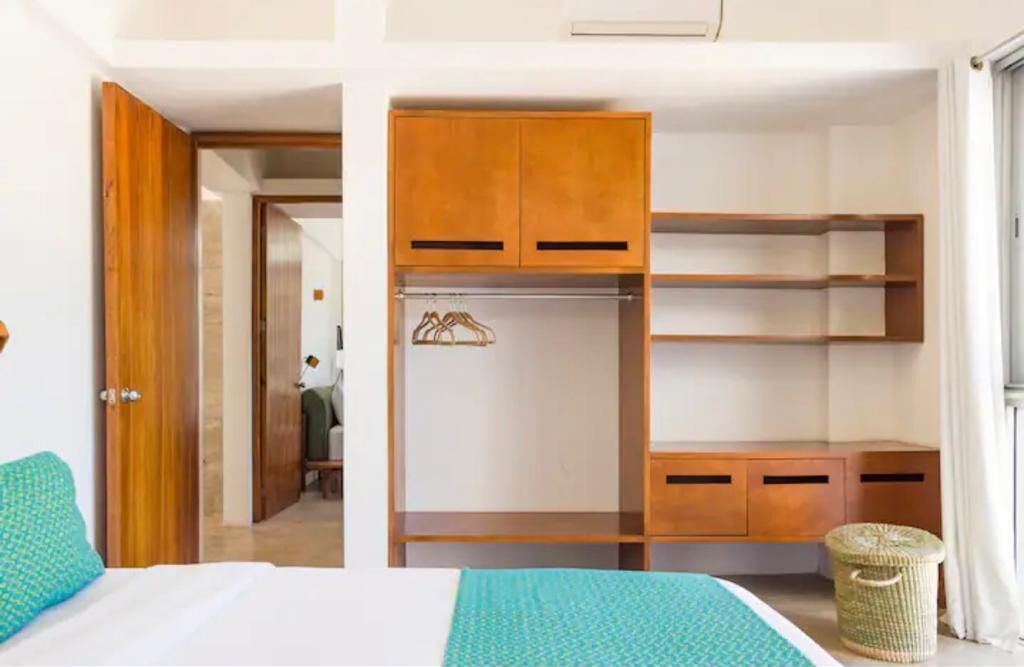 A bedroom with a bed, a wardrobe with multiple compartments, and a small wicker basket.