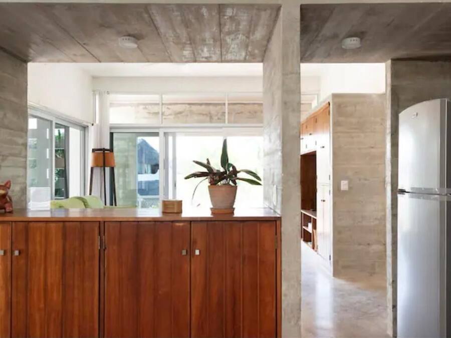 Una cocina moderna con armarios de madera, un refrigerador de acero inoxidable y un amplio ventanal que proporciona luz natural.
