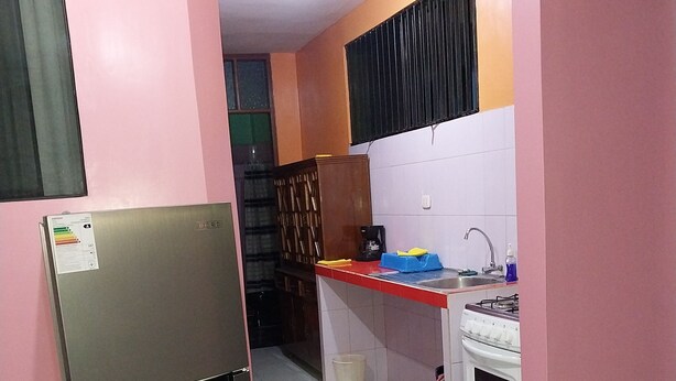 A compact kitchen with a refrigerator, stove, sink, and a small cabinet.