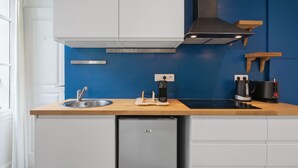 A compact kitchen with a built-in dishwasher, a sink, a coffee maker, and a kettle on the countertop. - Studio Bon'Air - Welkeys (Biarritz)