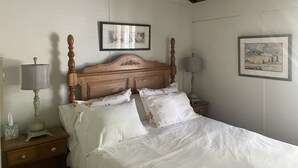 Een slaapkamer met een houten bed, witte beddengoed, twee nachtkastjes met lampen, en twee ingelijste foto's aan de muur.