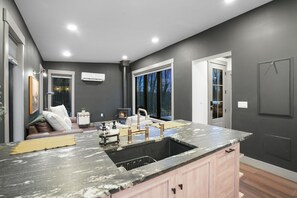 A modern kitchen with a large island, a built-in stove, and a view of the outdoors.
