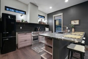 Une cuisine moderne dotée d’un îlot central, d’appareils électroménagers intégrés et d’une grande fenêtre.