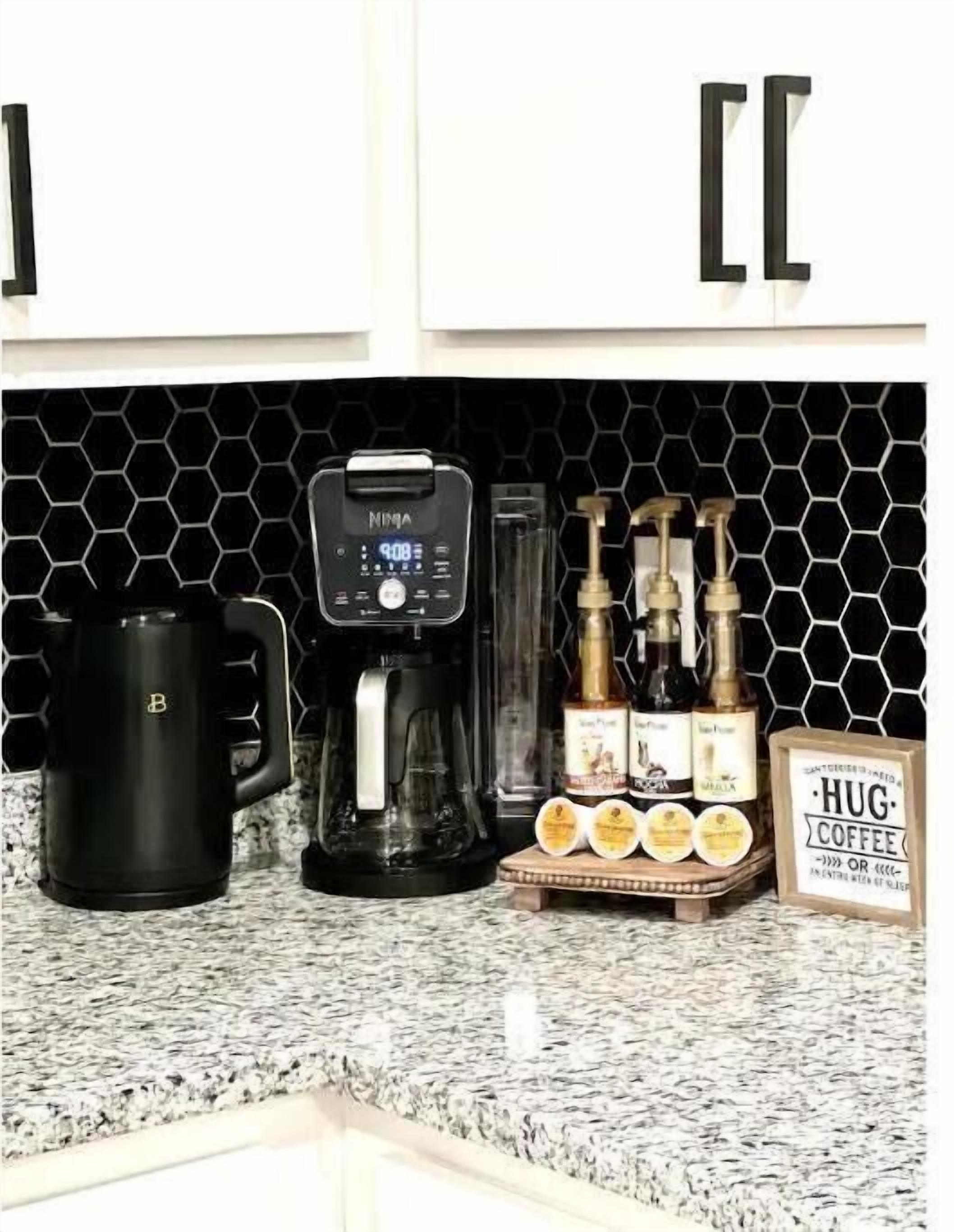 A kitchen counter with a coffee maker, a mug, and a coffee station with pumps and containers.