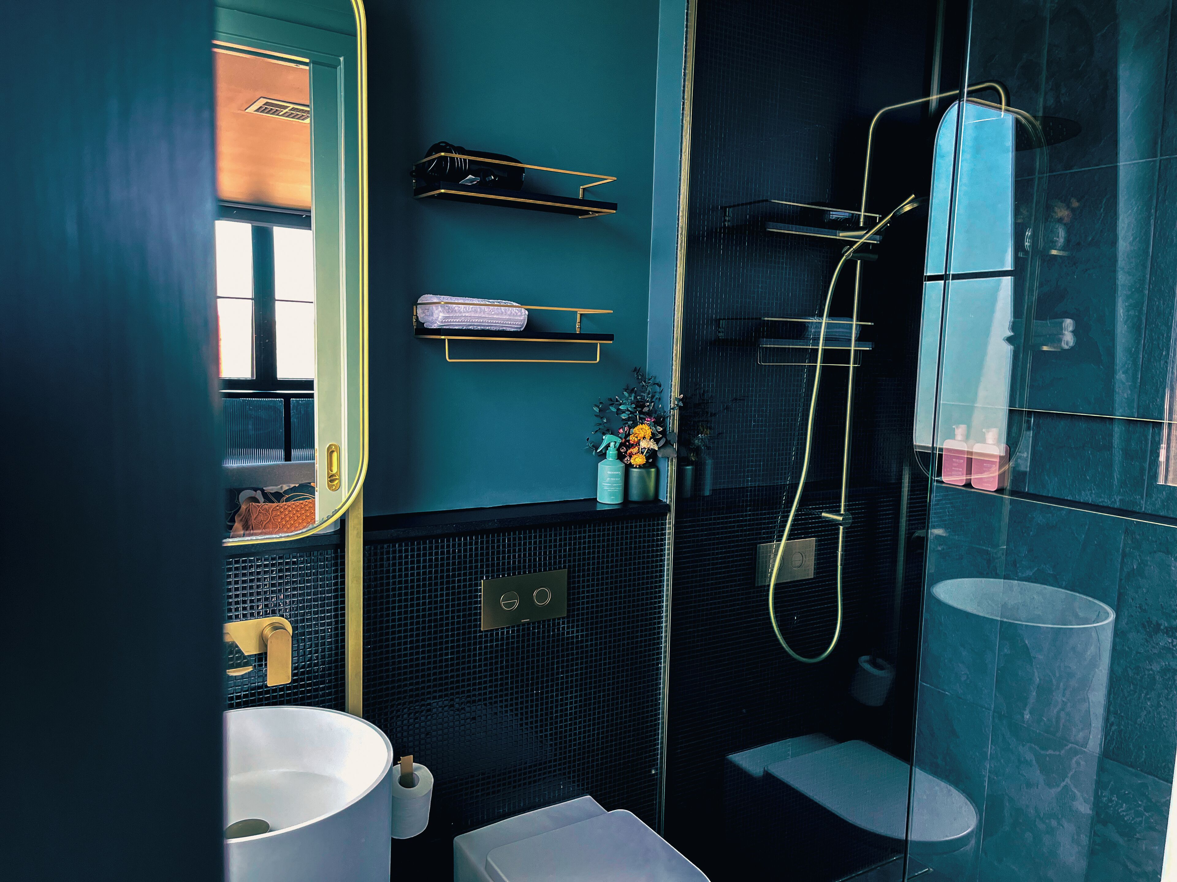 A modern bathroom with a glass-enclosed shower, a white sink, and a mirror.