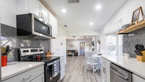 A modern kitchen with white cabinets, stainless steel appliances, and a wooden floor. - Stylish, Spacious Entire Hm 4/2 in nice Killeen neighborhood (Killeen)