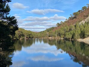 A serene lake surrounded by dense forest and hills.