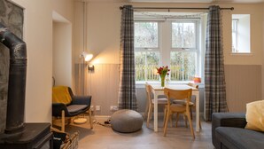 Una sala de estar acogedora con chimenea, una zona de comedor con mesa y sillas, y un sofá.