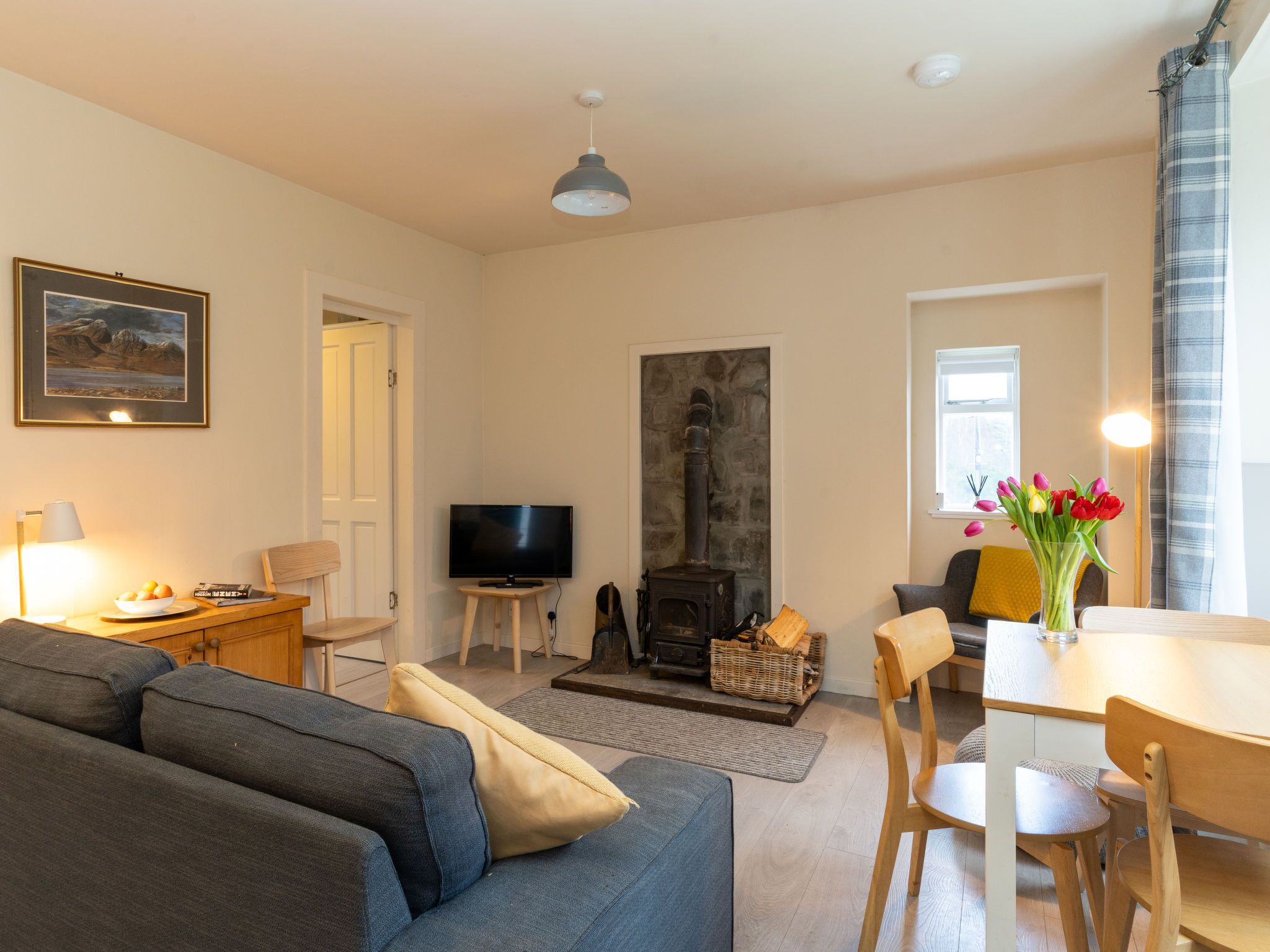 A living room with a sofa, TV, fireplace, dining table, and chairs.