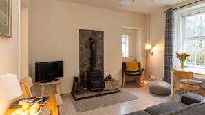 Una sala de estar acogedora con chimenea, televisor y comedor con mesa y sillas.