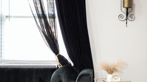 Ein modernes Wohnzimmer mit einem schwarzen Sofa, einem runden Couchtisch und einem Marmorboden.