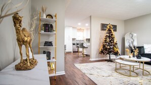 Ein modernes Wohnzimmer mit einem Marmortisch, einer goldenen Statue und einem Weihnachtsbaum.