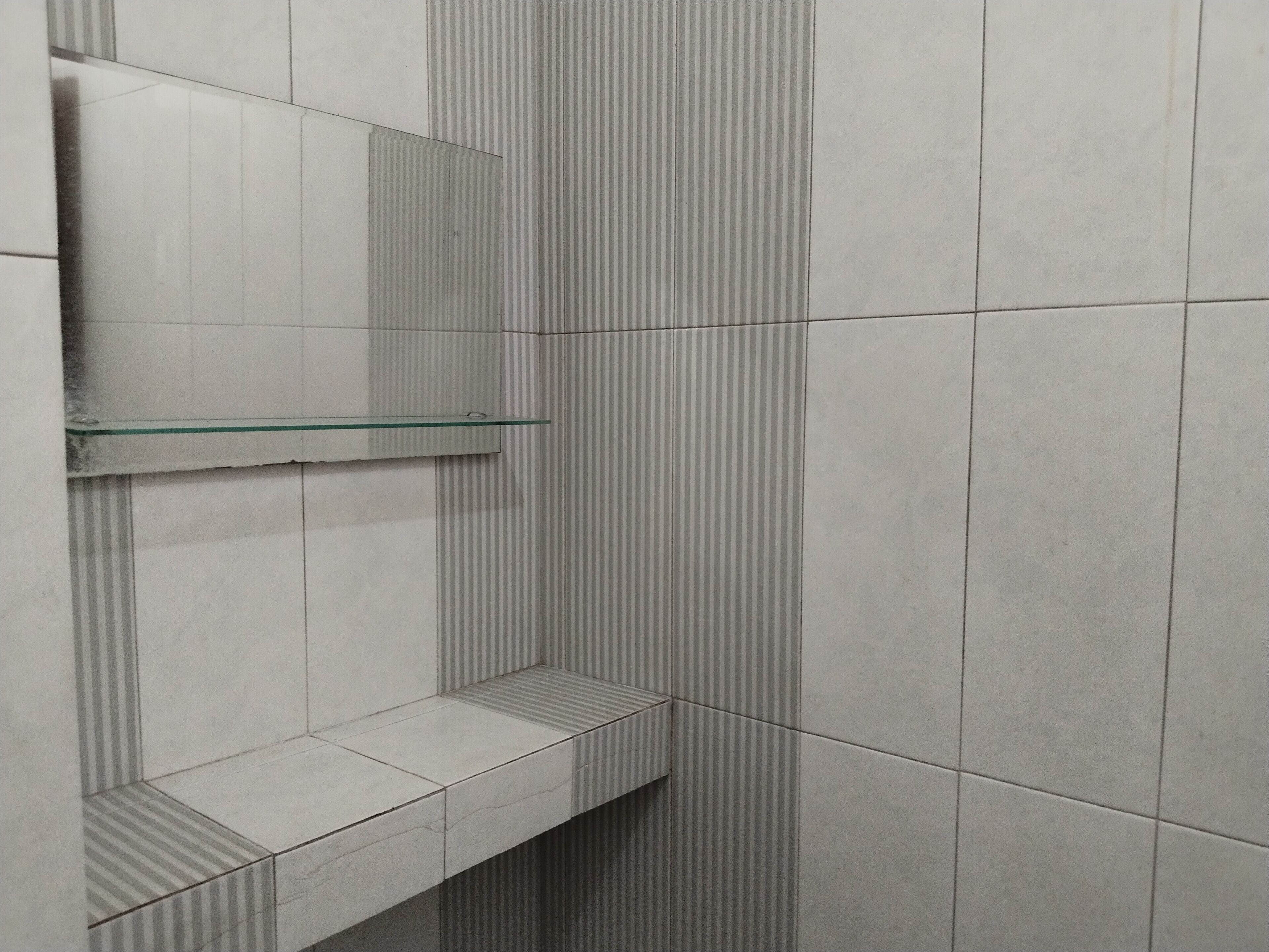 A bathroom with a glass shelf and striped tiles.