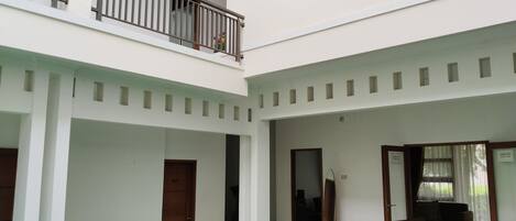 A multi-level building with a central open area, balconies, and a staircase leading to the upper floor.
