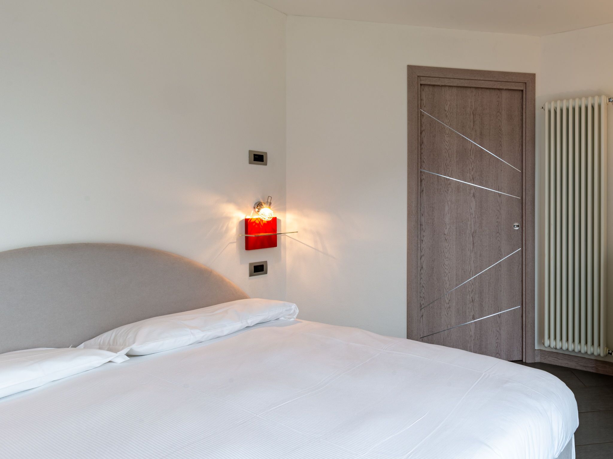 A bedroom with a bed, a wooden door, and a radiator.