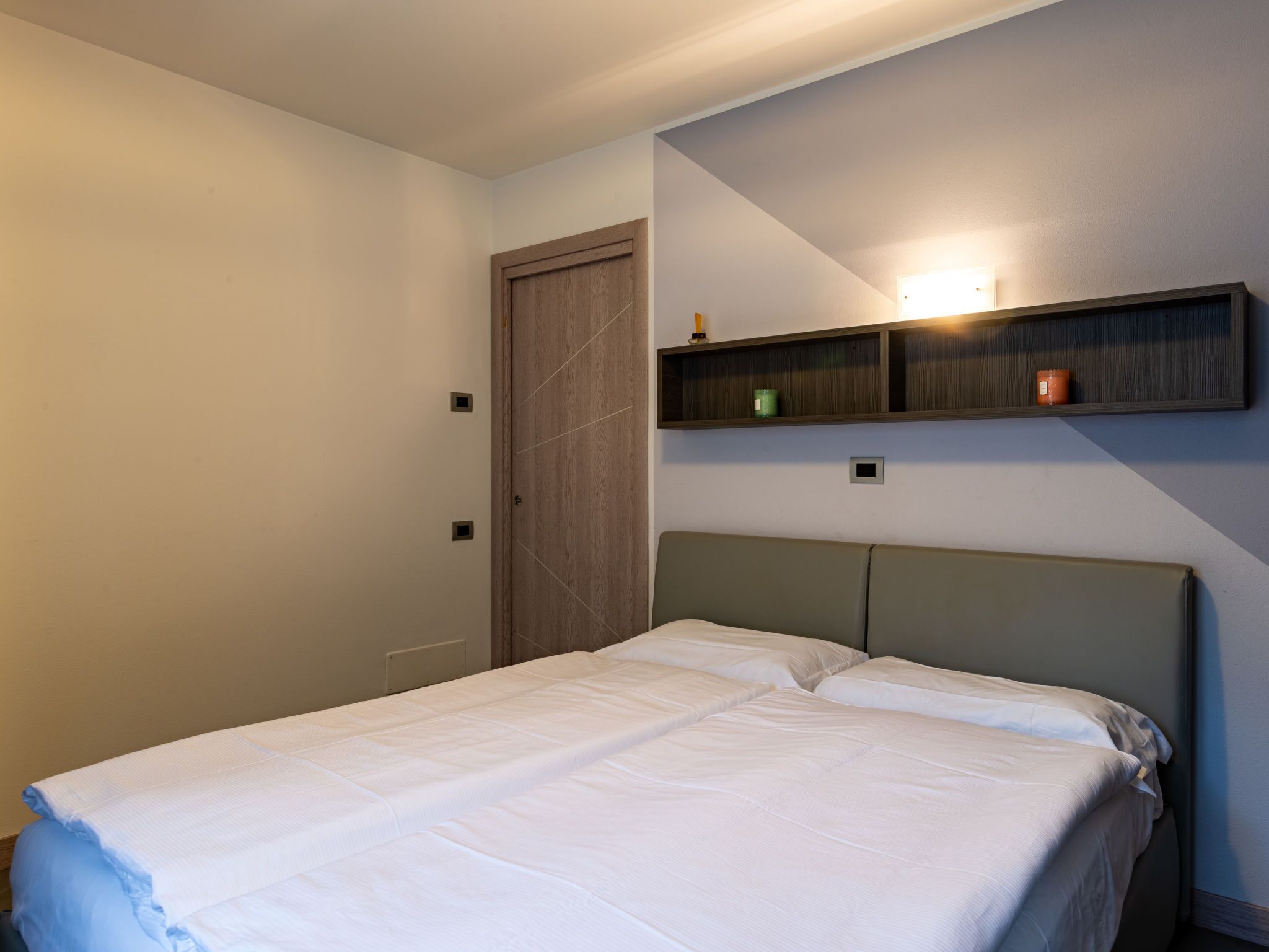 Ein Schlafzimmer mit Bett, Tür und Ablagefläche mit zwei Kerzen.