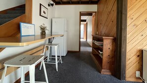 A compact kitchen with a wooden countertop, a white refrigerator, and a small stool.