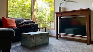 A living room with a large window, a sofa, a television, and a suitcase.