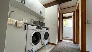A laundry room with two front-loading washing machines, a microwave, and a towel rack.