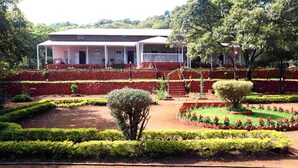 Un bâtiment doté d’un porche abrité et d’un jardin agrémenté de haies et de parterres de fleurs.