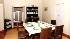 Une salle à manger avec une table mise pour quatre personnes, entourée de chaises en bois. Un buffet orné d’assiettes décoratives est adossé au mur.