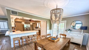 Una cocina amplia con isla central, mesa de comedor de madera y taburetes de bar.