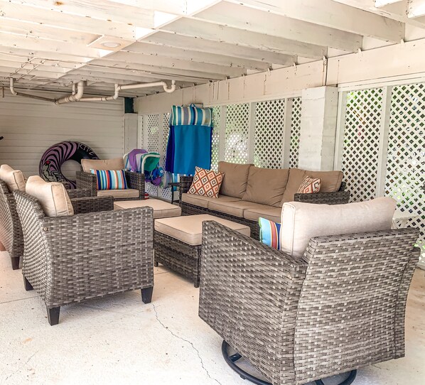 A covered outdoor seating area with wicker furniture and a blue tarp.